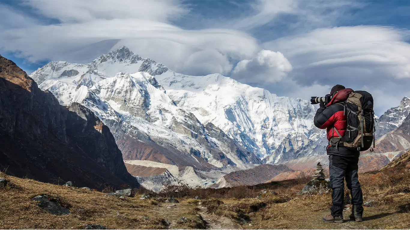 Photographer overlooking Kanchenjunga and Goecha Peak near Lamuney campsite on the Goechala Trek route in Sikkim