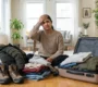 Confused woman packing winter clothes and hiking boots before traveling to Sikkim