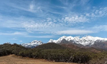 Panoramic Himalayan mountain view along the Dzongri Trek trail in West Sikkim under a clear blue sky.