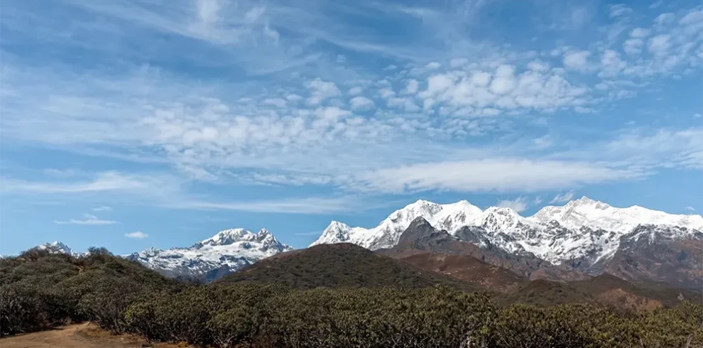 Panoramic Himalayan mountain view along the Dzongri Trek trail in West Sikkim under a clear blue sky.